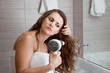 dressed in towel beautiful woman using fen at modern bathroom