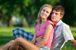 Two young lovers sitting on the lawn in the park