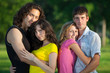 Four young people embrace and stand in the park