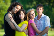 Four young people embrace and stand in the park
