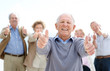 Joyful mature man showing thumbs up sin with his friends at back