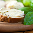 Baguette with brie and herbs on wooden bread board