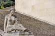 Femme sculptée souriante devant un escalier.