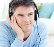 Portrait of a positive man with headphones lying on the floor