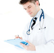 Serious male doctor writing on a clipboard