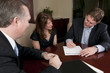 Man signing contract with wife and attorney