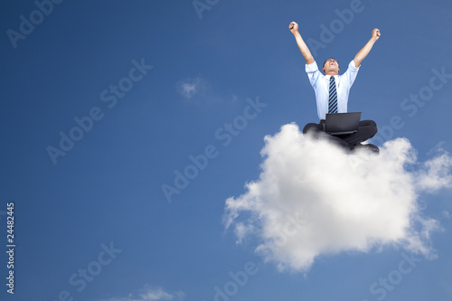 Photo: young businessman with computer sitting on the cloud young businessman with computer sitting on the cloud