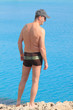 Foto: Mann in Badehose blickt auf das weite türkise Meer Zyperns Mann in Badehose blickt auf das weite türkise Meer Zyperns