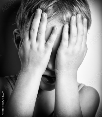 Photo : BW portrait of sad crying little boy covers his face with hands BW portrait of sad crying little boy covers his face with hands