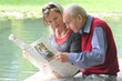 Großvater und Enkelin beim Zeitunglesen im Grünen am Teich Großvater und Enkelin beim Zeitunglesen im Grünen am Teich