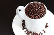Coffee mug and saucer filled with fresh coffee beans Coffee mug and saucer filled with fresh coffee beans