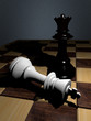 A white chess king is attack by a black chess queen
