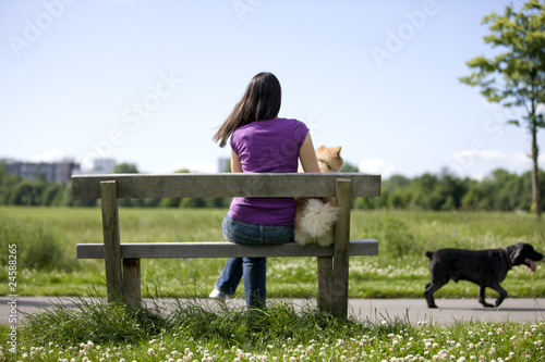 Foto: A young woman and her dog sitting on a bench A young woman and her dog sitting on a bench