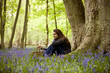A young woman sitting under a tree, holding a picnic basket