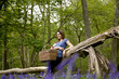 A young woman leaning against a tree, holding a picnic basket