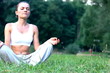 Woman sitting on the grass in park and meditating, dolly shot