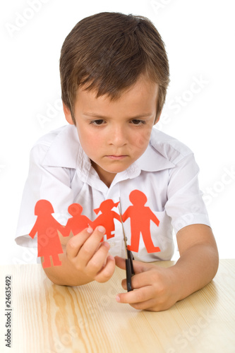 Photo: Sad kid cutting up paper people family - divorce concept Sad kid cutting up paper people family - divorce concept