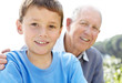 Little boy smiling with his grandfather in background