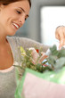Beautiful young woman with a flower bouquet reading a card