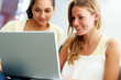 Happy young females enjoying using laptop