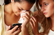 Foto: Young girl holding a mobile phone in sorrow with a friend consol Young girl holding a mobile phone in sorrow with a friend consol