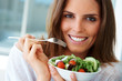 Joyful young lady eating fruit salad