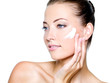 Photographie : woman applying moisturizer cream on cheek