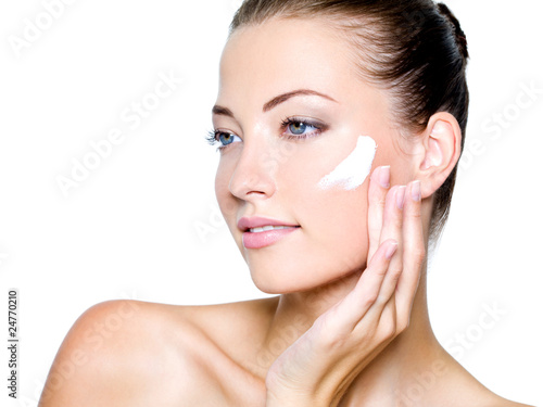 Photo: woman applying moisturizer cream on cheek woman applying moisturizer cream on cheek