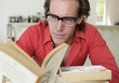 Photo: Young man with glasses reading a book Young man with glasses reading a book