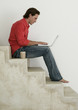 Photo: Male working on laptop on stairs at home Male working on laptop on stairs at home