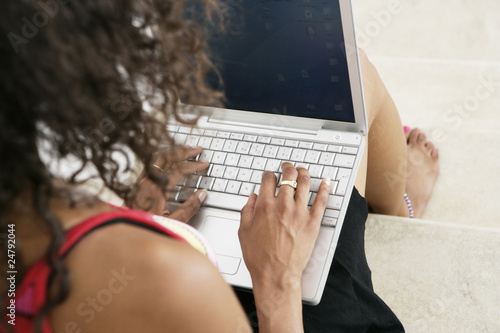 Photo: Young female typing on laptop at home Young female typing on laptop at home