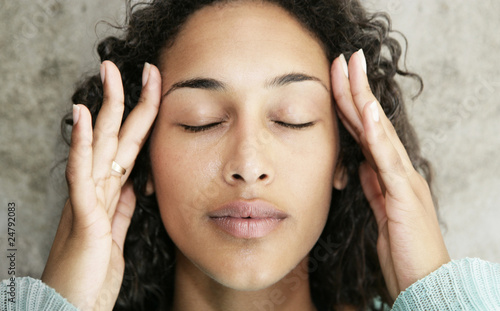 Photo: Young female with headache and massaging her temples Young female with headache and massaging her temples