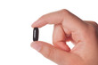 female hand holding a black capsule, isolated female hand holding a black capsule, isolated