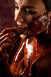 Woman covered in melted chocolate tastes chocolate bar and enjoy