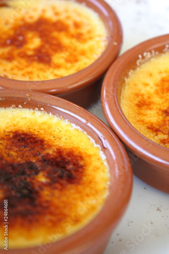 Photo: Three ramekins of crème brûlée on a french restaurant table. Three ramekins of crème brûlée on a french restaurant table.