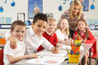 Group Of Primary Schoolchildren And Teacher Working At Desks In