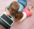 Little girl and boy lying in front of laptop