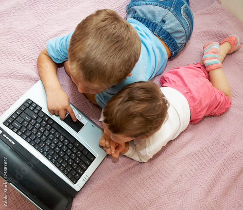 Photo: Little girl and boy lying in front of laptop Little girl and boy lying in front of laptop