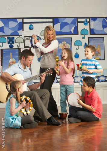 Photo: Teachers Playing Guitar With Pupils Having Music Lesson In Class Teachers Playing Guitar With Pupils Having Music Lesson In Class