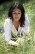 jeune fille seule lisant livre dans herbe