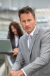 Businessman standing in front of offices outside Businessman standing in front of offices outside