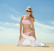 Woman posing on the beach with white silk scarf blowing by wind