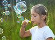 little girl blowing soap bubbles at sunset