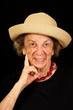 Up-close face of wrinkled elderly lady with hat on and big smile