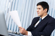 Businessman with document and laptop at office