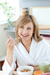Bright woman eating cereals wearing a bath robe Bright woman eating cereals wearing a bath robe