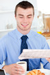 Happy businessman reading the newspaper drinking coffee