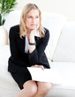 Frustrated businesswoman holding a paper sitting on the sofa