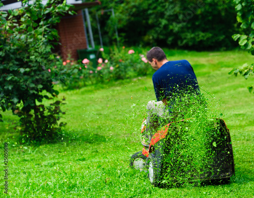 Photo: Ride-on lawn mower cutting grass. Focus on grasses in the air Ride-on lawn mower cutting grass. Focus on grasses in the air