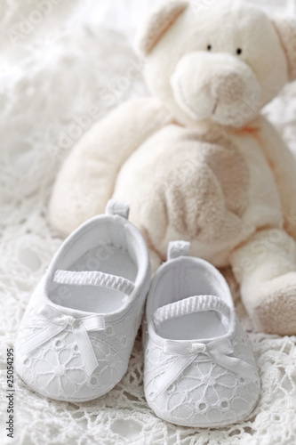 Photo: Baby girl shoes and teddy bear on white background Baby girl shoes and teddy bear on white background